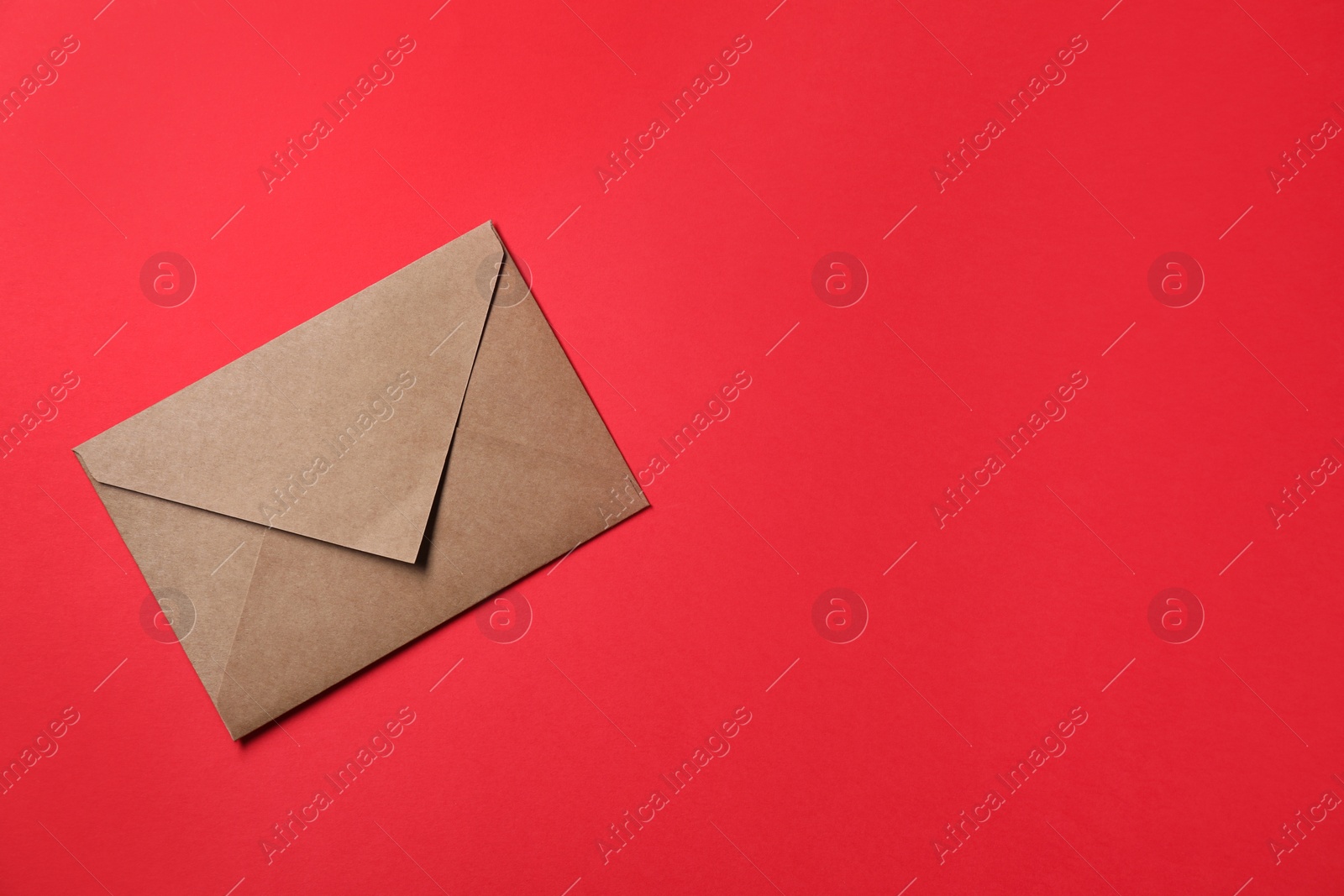 Photo of Letter envelope on red background, top view. Space for text