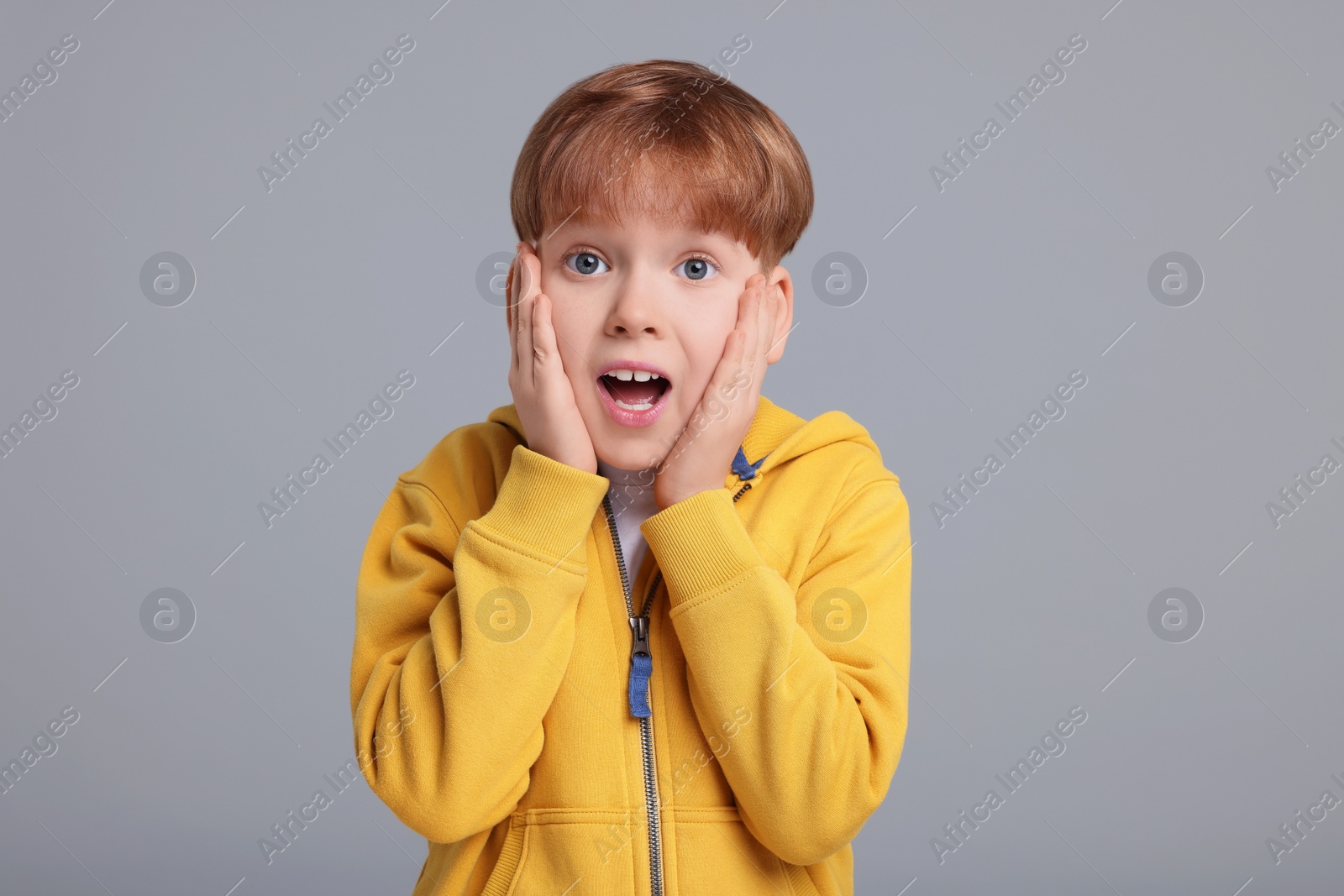 Photo of Portrait of surprised little boy on grey background