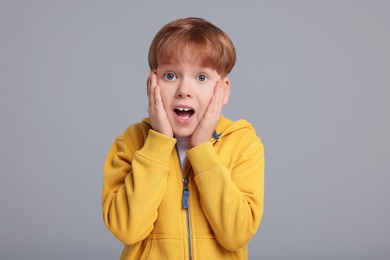 Portrait of surprised little boy on grey background