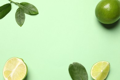 Photo of Whole and cut fresh ripe limes with leaves on light green background, flat lay