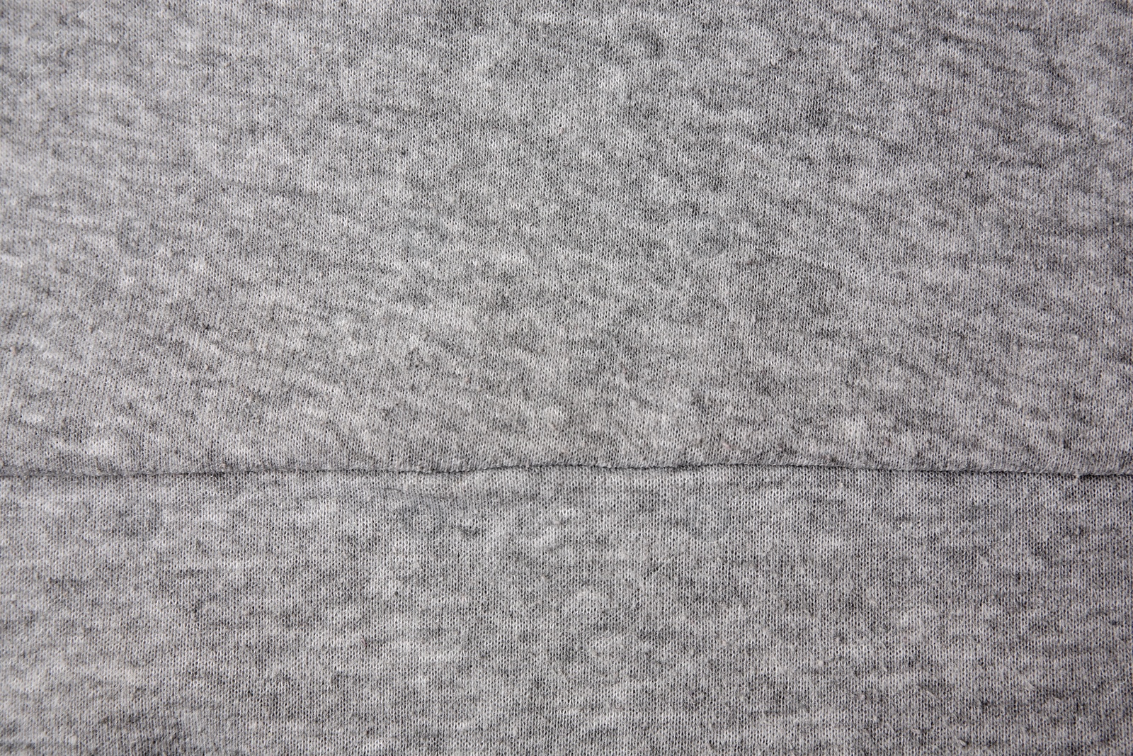 Photo of Light grey cloth with lint as background, top view. Before using fabric shaver