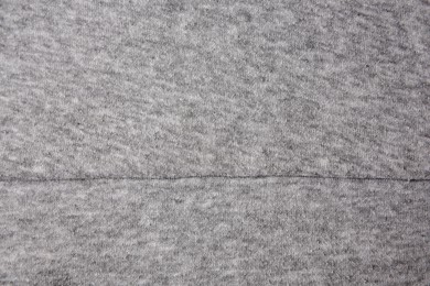 Photo of Light grey cloth with lint as background, top view. Before using fabric shaver