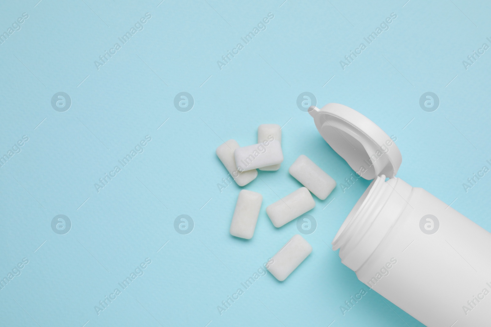 Photo of Jar with chewing gums on light blue background, flat lay. Space for text