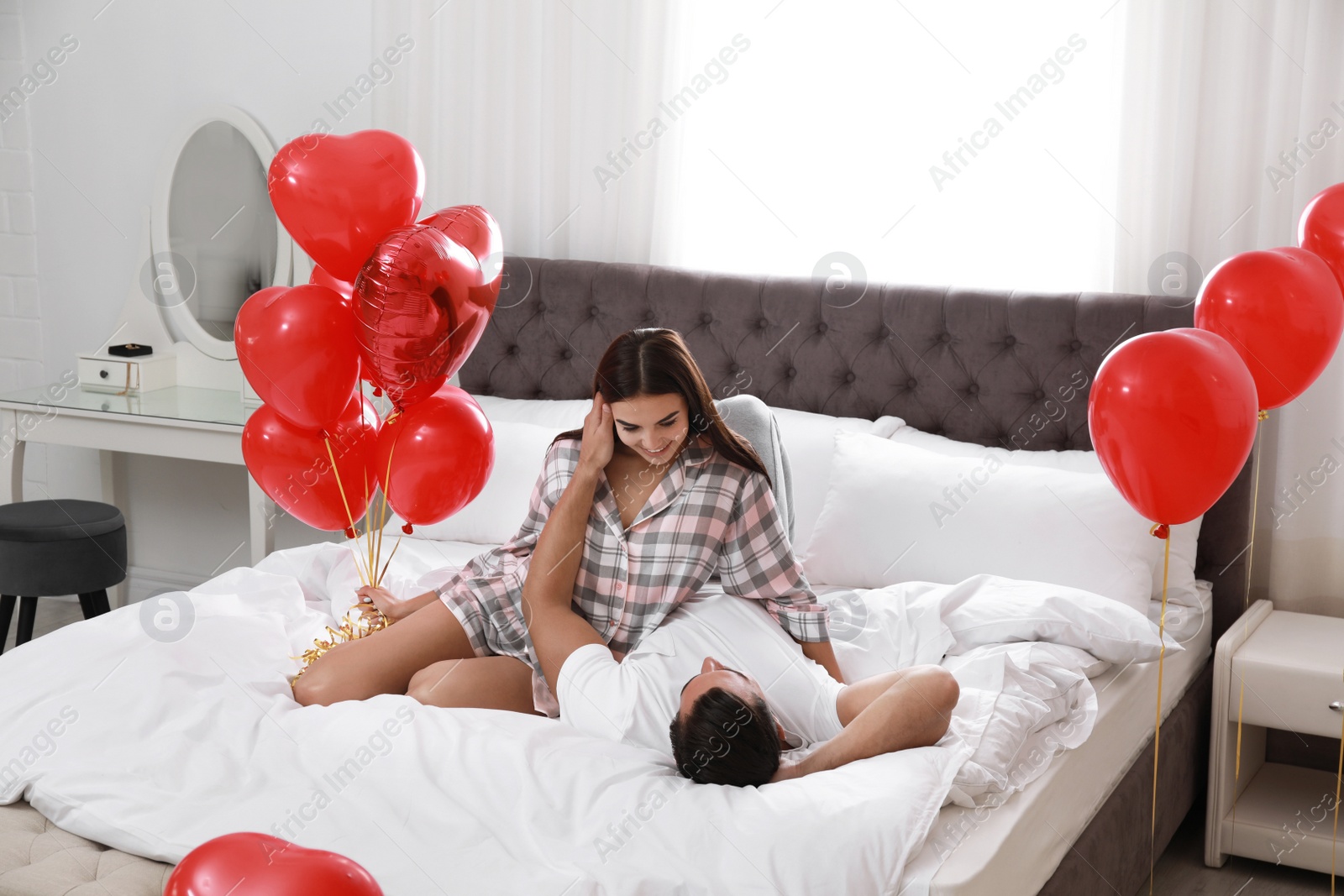 Photo of Beautiful couple with heart shaped balloons in bedroom