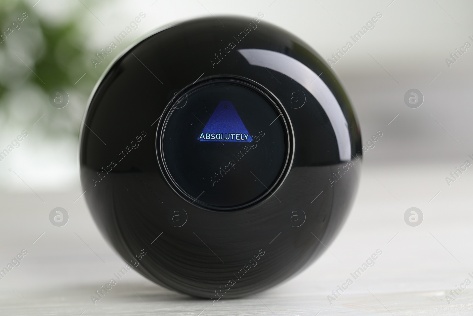 Photo of Magic eight ball with prediction Absolutely on light table, closeup