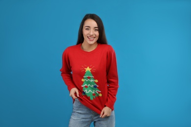 Young woman in Christmas sweater on blue background