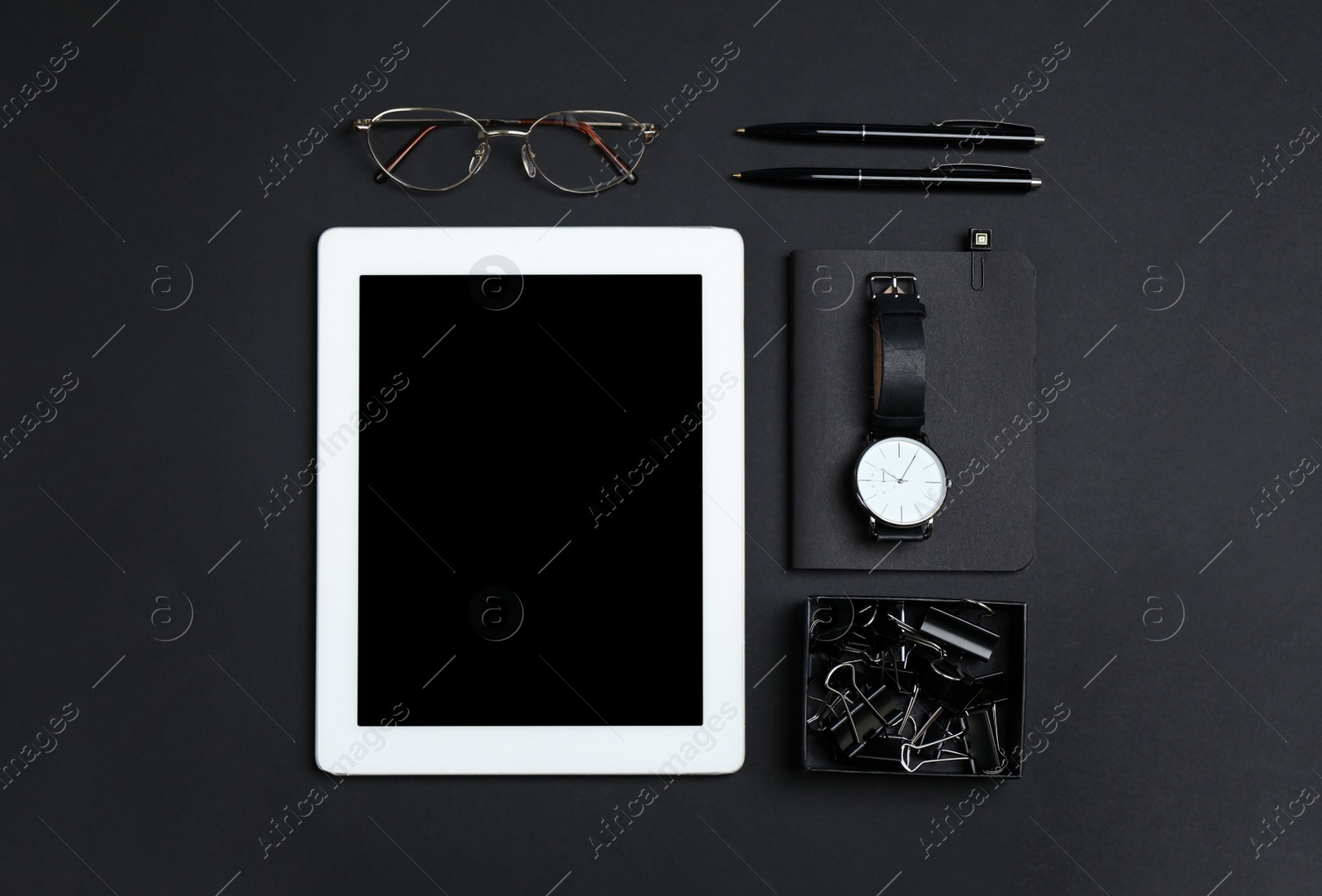 Photo of Tablet, watch, glasses and stationery on black background, flat lay