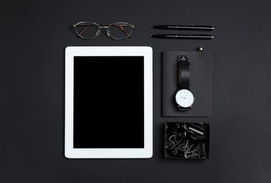 Tablet, watch, glasses and stationery on black background, flat lay