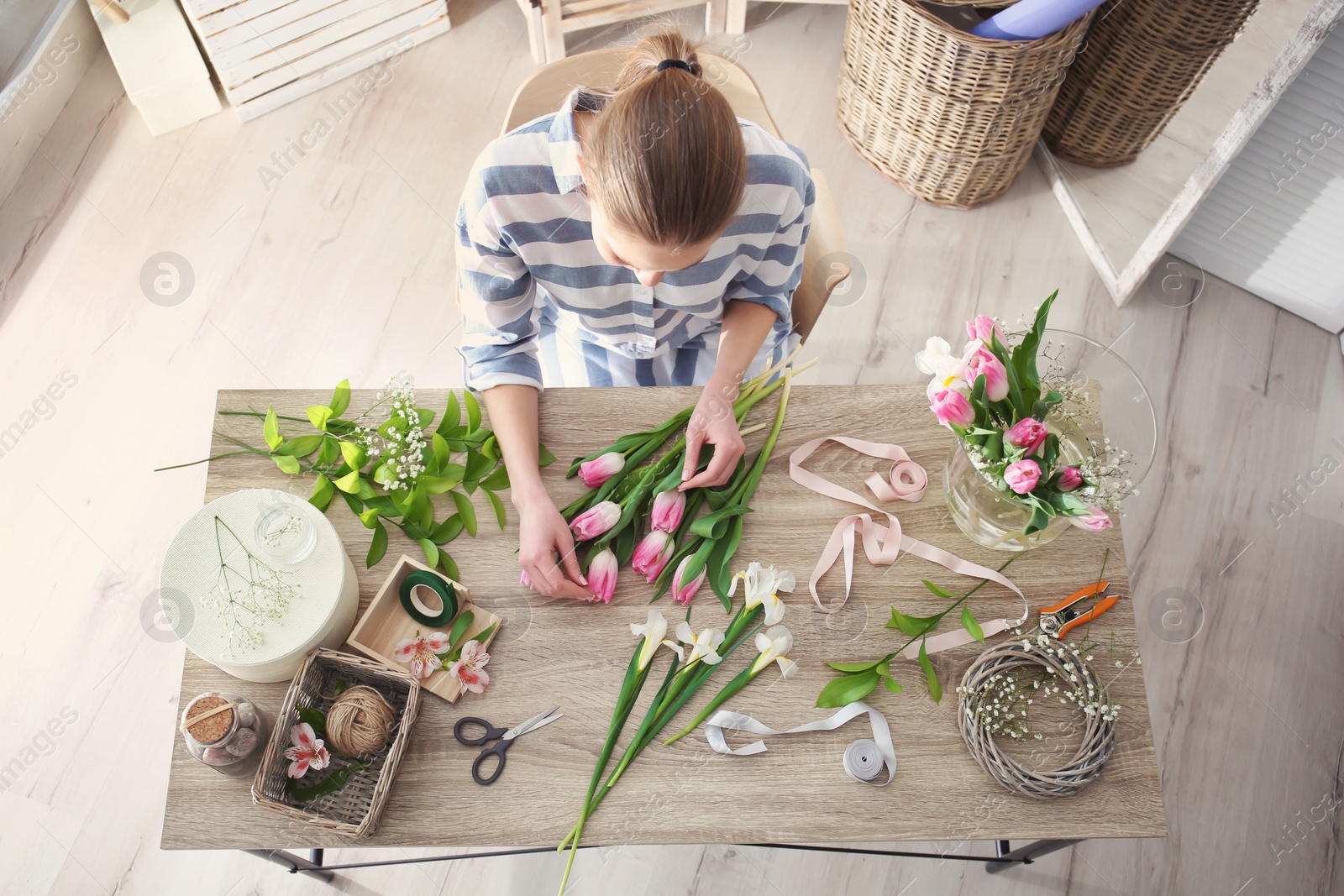 Photo of Female decorator creating beautiful bouquet at table