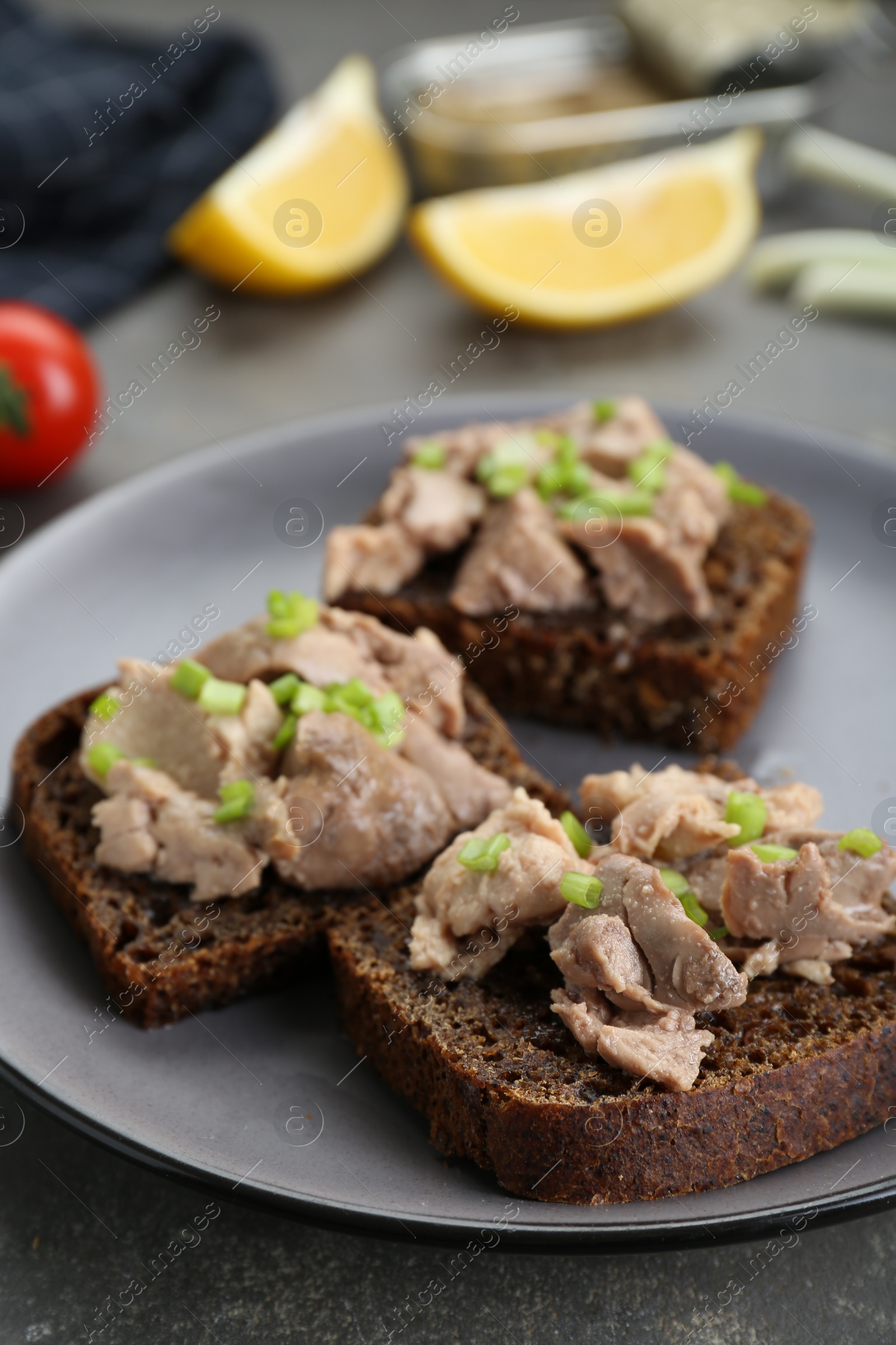 Photo of Tasty sandwiches with cod liver and green onion on light grey table