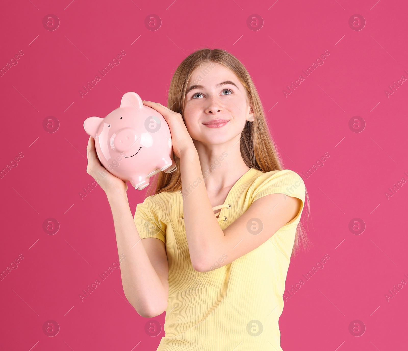 Photo of Teen girl with piggy bank on color background