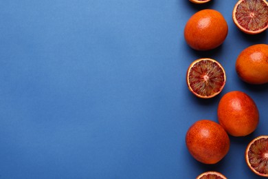 Photo of Many ripe sicilian oranges on blue background, flat lay. Space for text