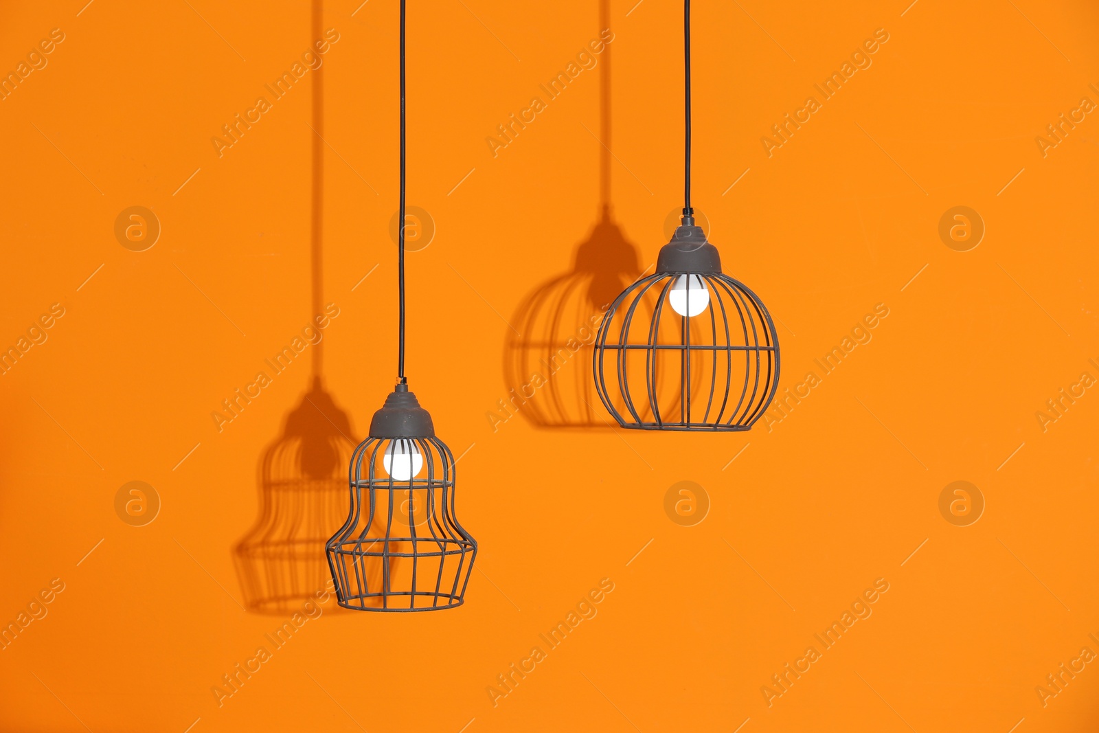 Photo of Stylish pendant lamps hanging on color background