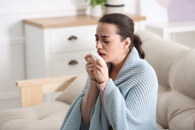 Photo of Young woman suffering from runny nose in living room