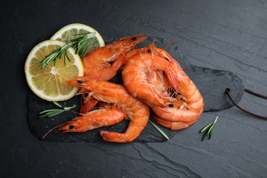 Photo of Delicious cooked shrimps with lemon and rosemary on black table, flat lay