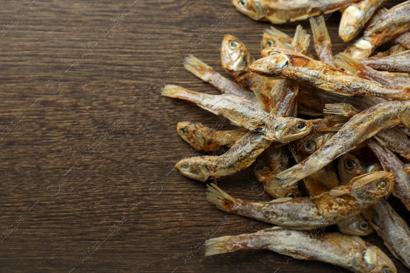 Photo of Delicious dried anchovies on wooden table, closeup. Space for text