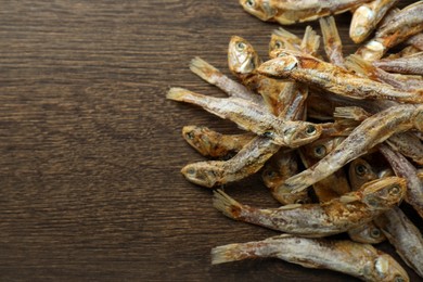 Photo of Delicious dried anchovies on wooden table, closeup. Space for text