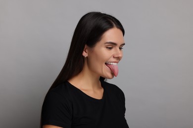 Photo of Personality concept. Emotional woman showing tongue on grey background
