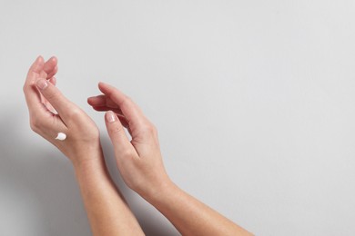 Photo of Woman with cosmetic cream on hand against light grey background, top view. Space for text