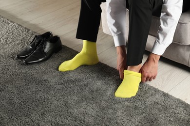 Photo of Man putting on yellow socks indoors, closeup