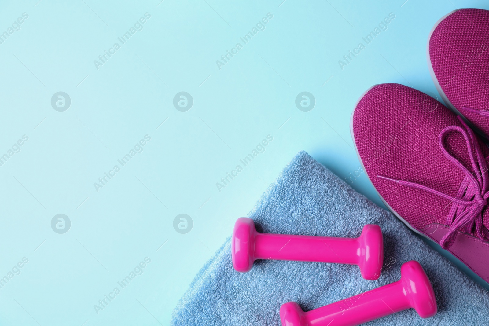 Photo of Vinyl dumbbells, sneakers and towel on color background, flat lay. Space for text