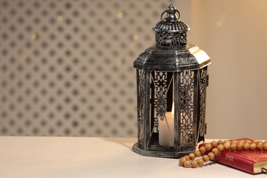 Arabic lantern, Quran and misbaha on white table. Space for text