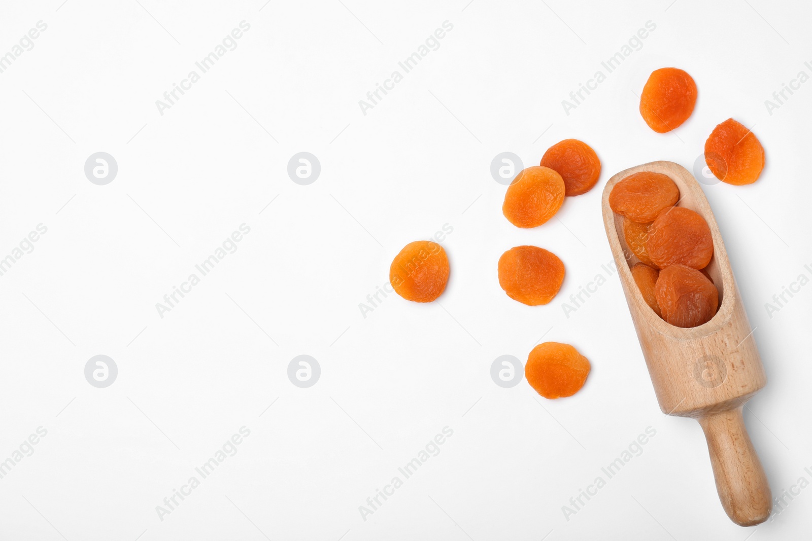 Photo of Wooden scoop of dried apricots on white background, top view with space for text. Healthy fruit