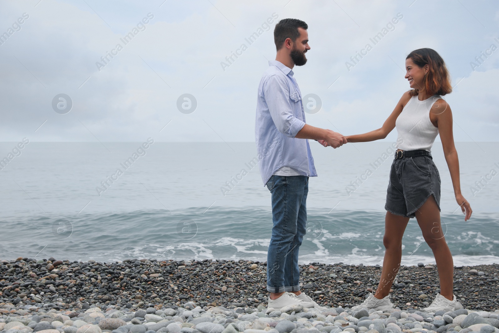 Photo of Happy young couple on beach near sea. Space for text