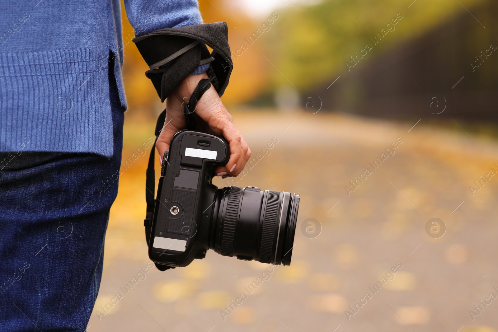 Photo of Photographer with professional camera outdoors on autumn day, closeup