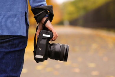 Photo of Photographer with professional camera outdoors on autumn day, closeup