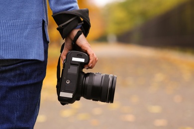 Photographer with professional camera outdoors on autumn day, closeup