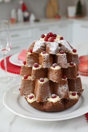 Photo of Delicious Pandoro Christmas tree cake decorated with powdered sugar and berries on white marble table