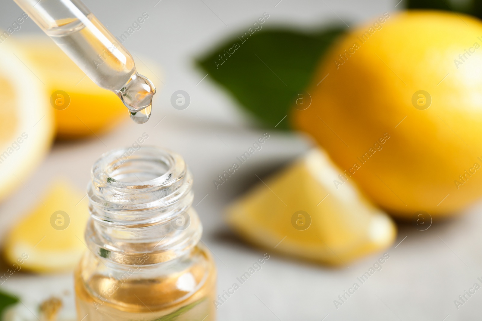 Photo of Citrus essential oil dripping from pipette into bottle, closeup. Space for text