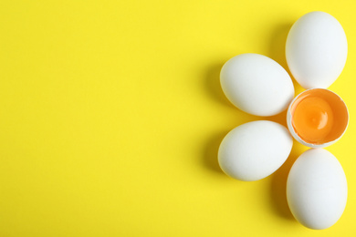 Photo of Fresh raw chicken eggs on yellow background, flat lay. Space for text