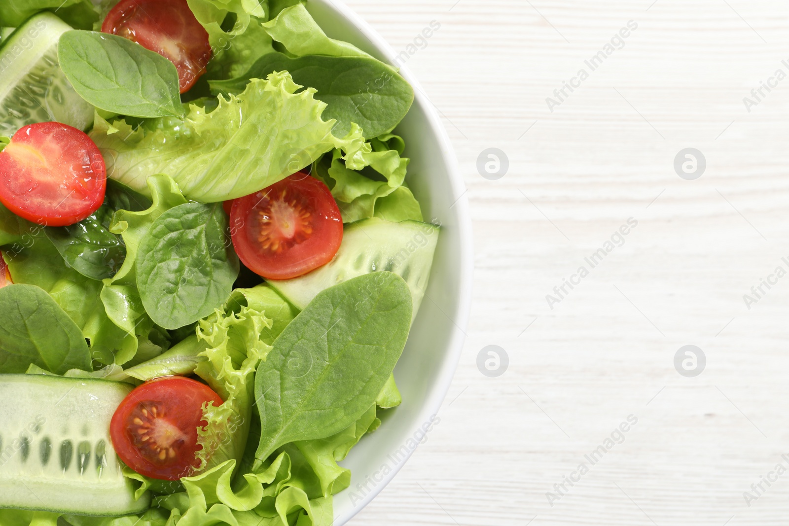 Photo of Delicious vegetable salad on white wooden table, top view. Space for text