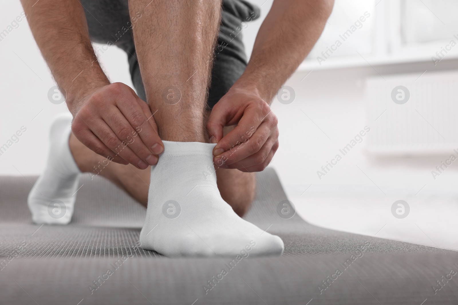 Photo of Man putting on white socks indoors, closeup