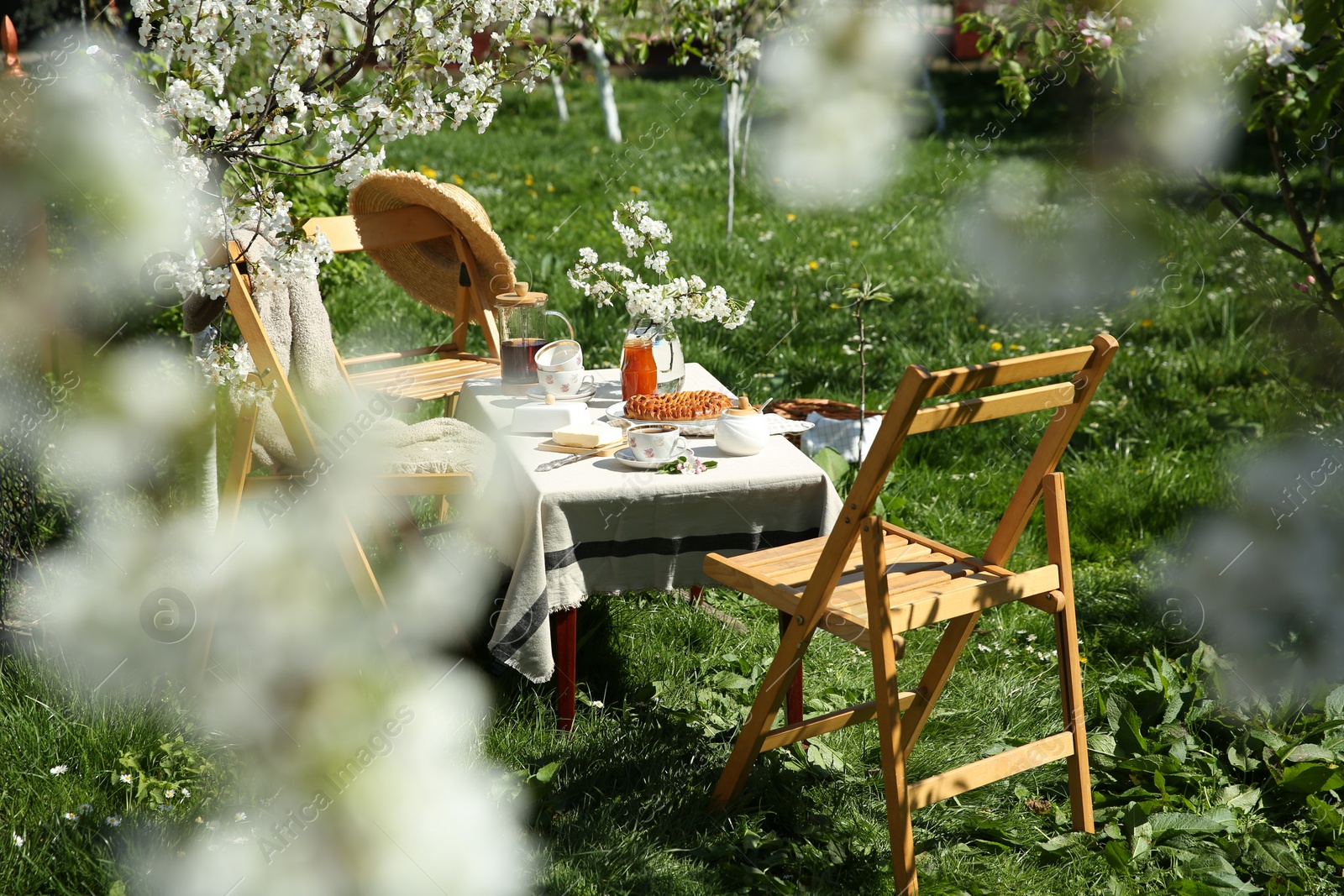 Photo of Beautiful table setting with spring flowers in garden on sunny day