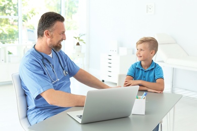 Photo of Male medical assistant consulting child in clinic