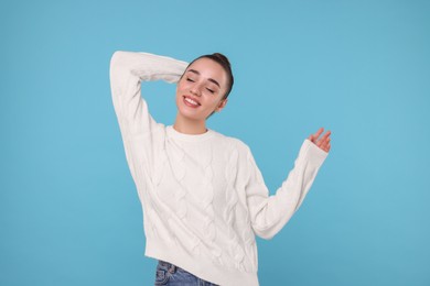 Beautiful young woman in stylish warm sweater on light blue background