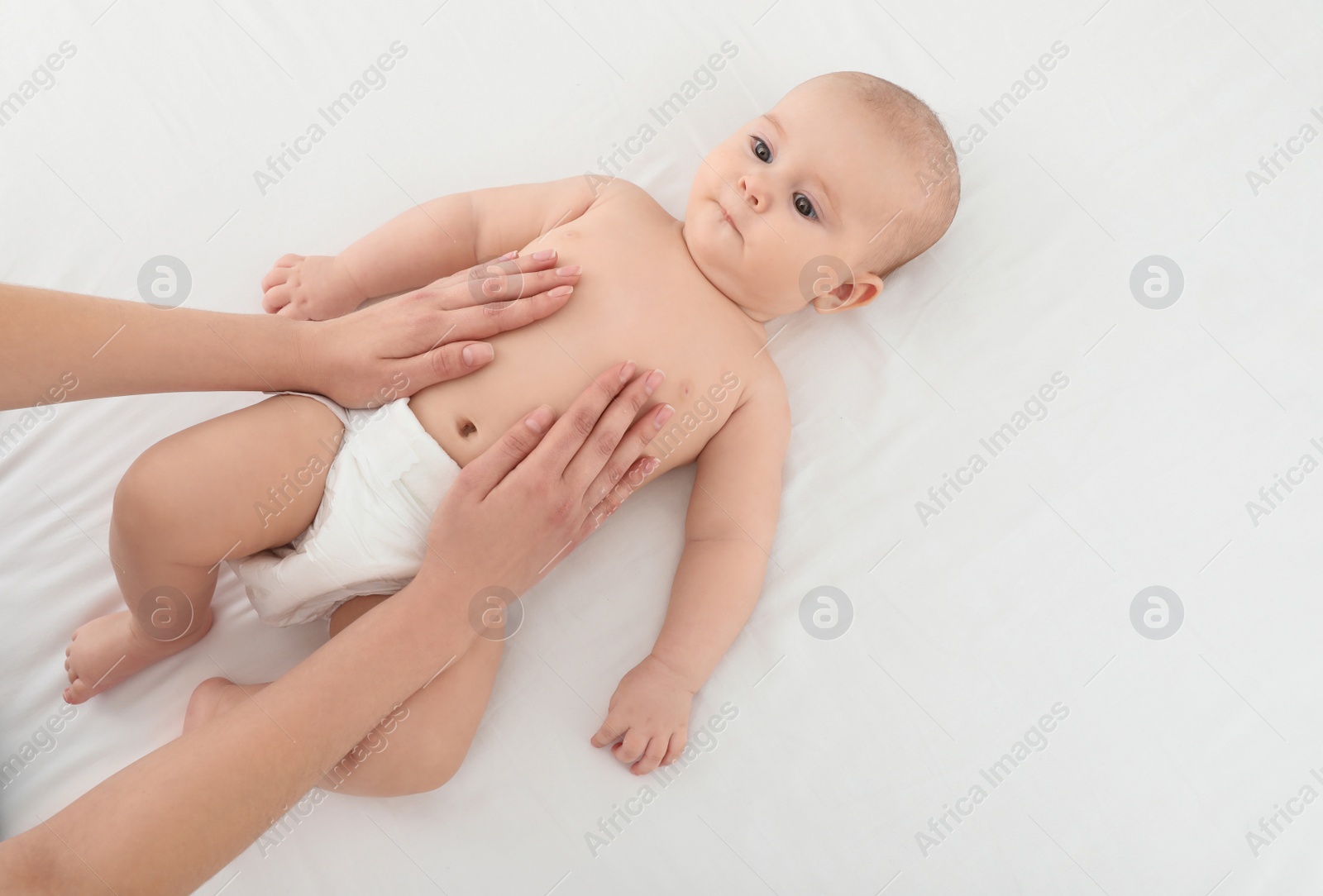 Photo of Top view of mother and her cute child on white bed, space for text. Baby massage and exercises