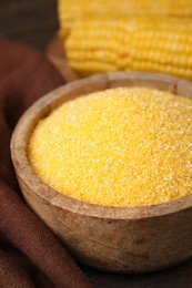 Photo of Raw cornmeal in bowl on table, closeup