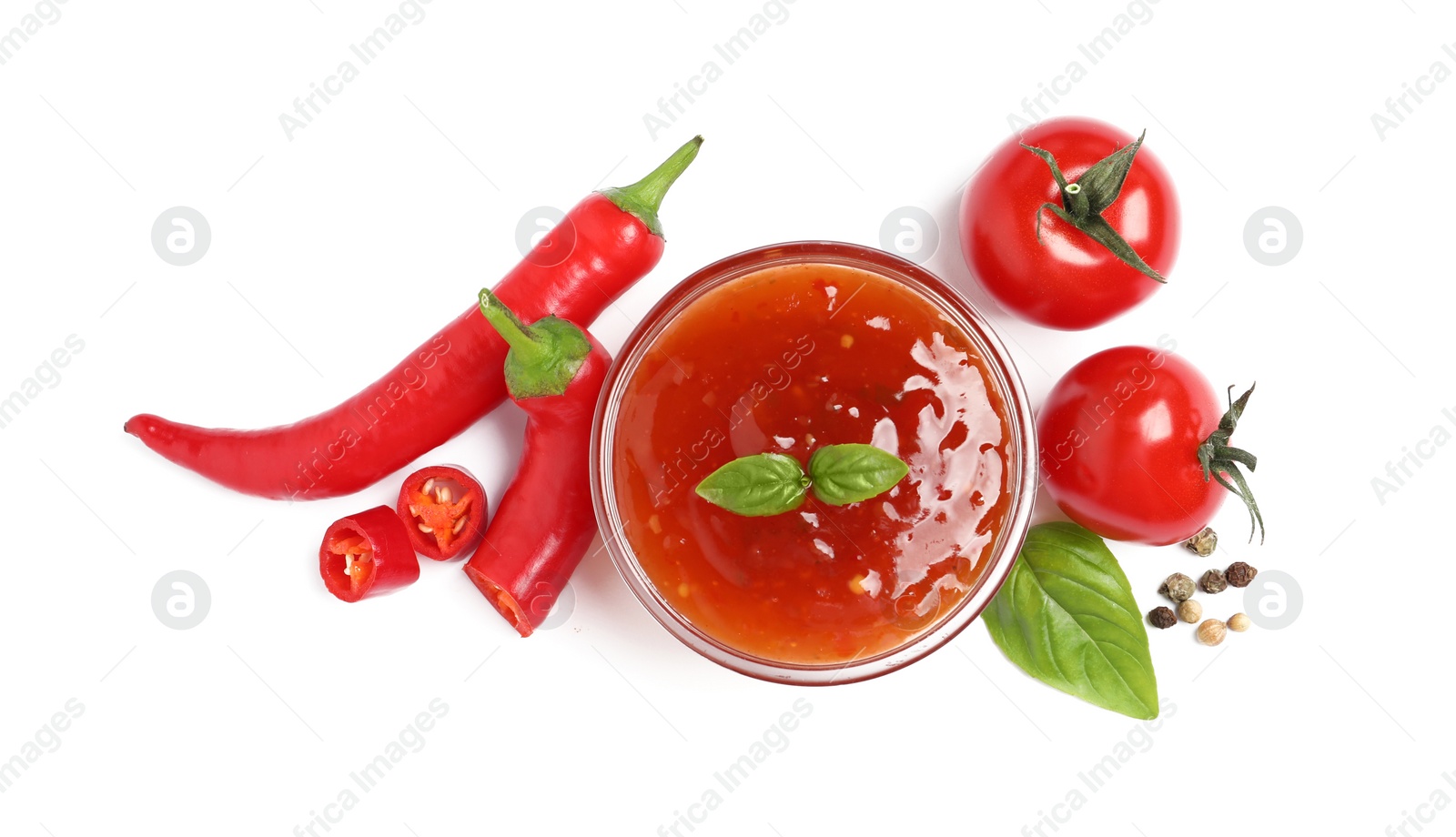 Photo of Spicy chili sauce and ingredients on white background, top view