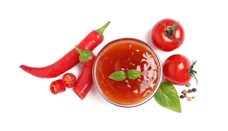 Photo of Spicy chili sauce and ingredients on white background, top view