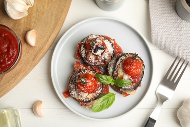 Photo of Baked eggplant with tomatoes, cheese and basil served on white wooden table, flat lay