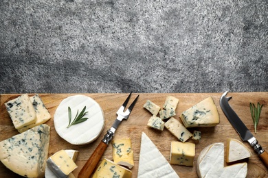 Photo of Cheese platter with specialized knife and fork on grey table, flat lay. Space for text