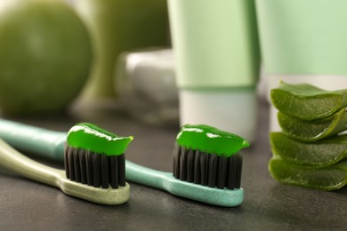 Brushes with aloe vera toothpaste on grey table, closeup