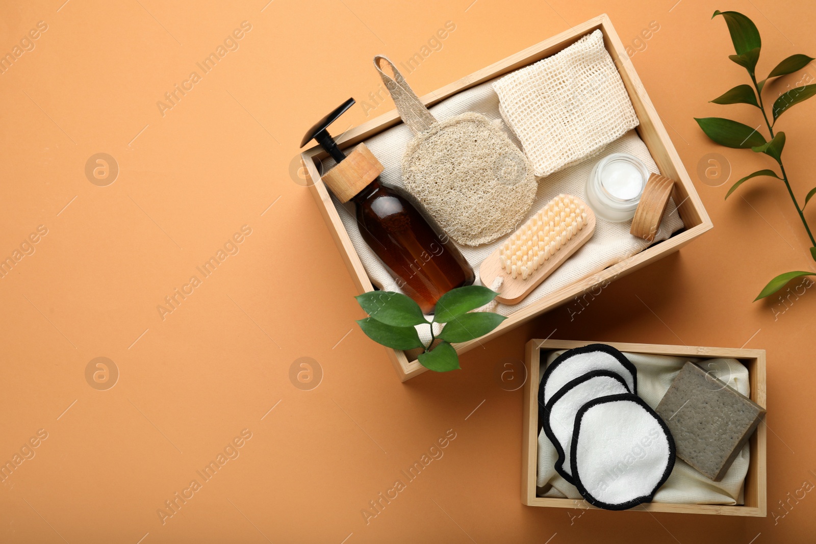 Photo of Eco friendly products in crates on pale orange background, flat lay. Space for text