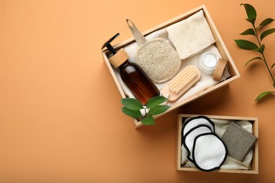 Eco friendly products in crates on pale orange background, flat lay. Space for text