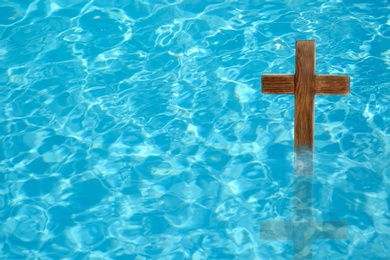 Image of Wooden cross in water for religious ritual known as baptism