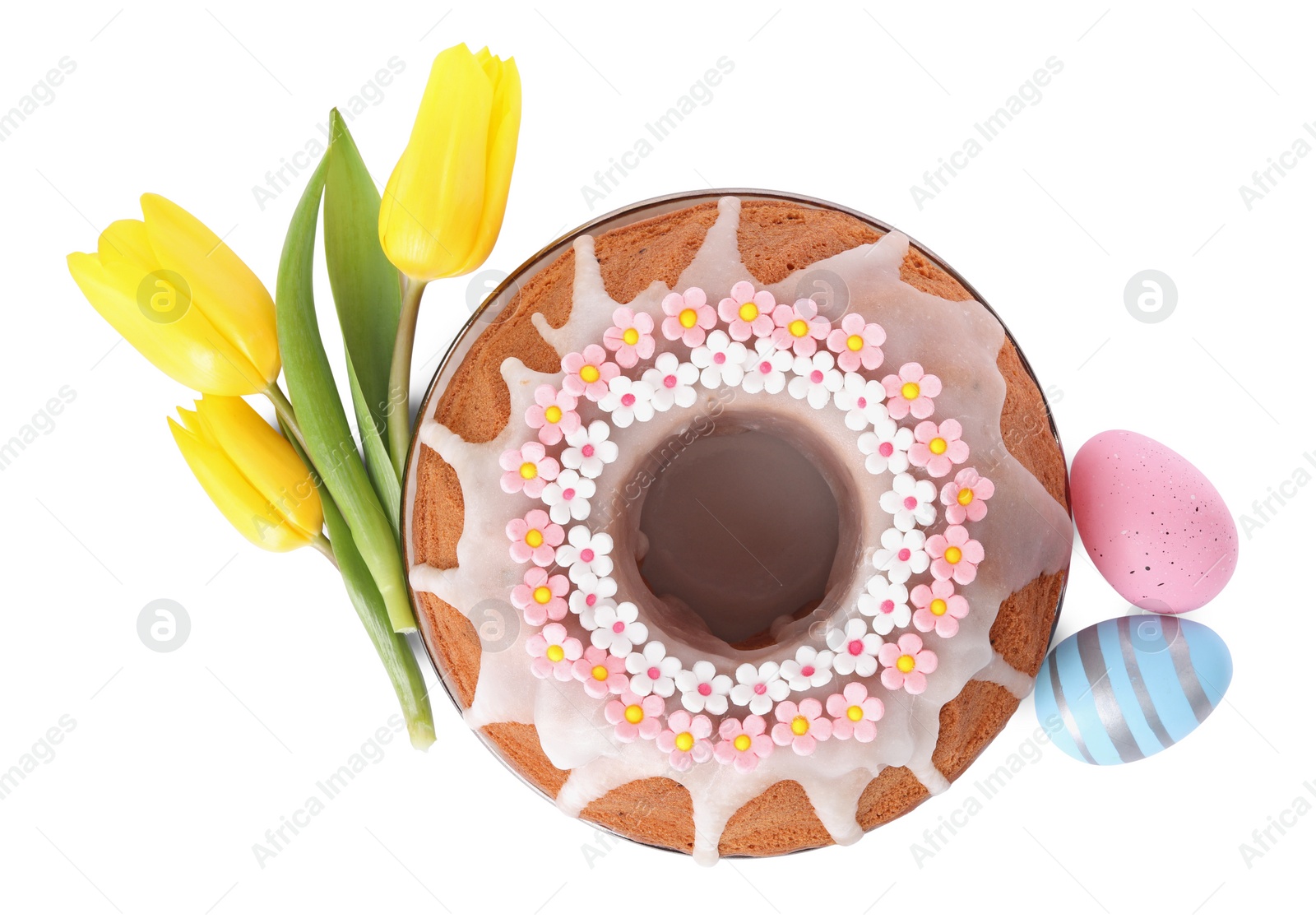 Photo of Festively decorated Easter cake, painted eggs and yellow tulips on white background, top view